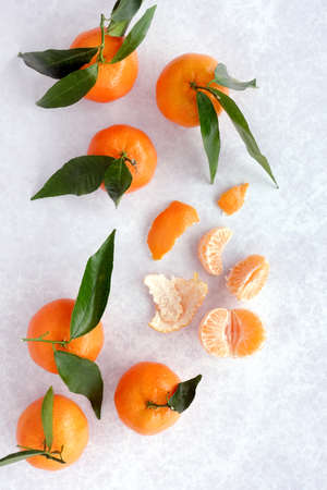 Top view of whole clementines with leaves, peel and segments on gray patterned background.の写真素材