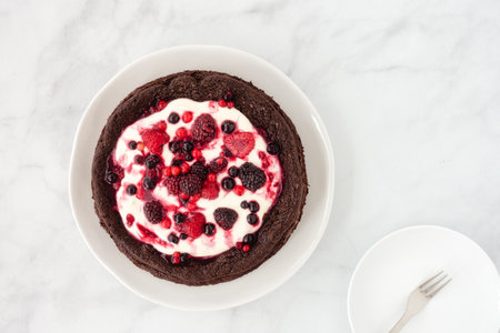 Chocolate cloud cake, flourless, with creme fraiche and frozen summer berries on marble background. Top view.の写真素材
