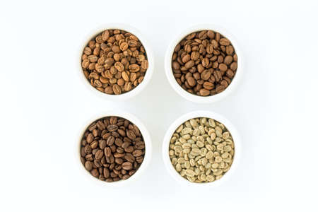 Light roast, medium roast, dark roast and green coffee beans in white ceramic ramekins isolated on white. Top view.の写真素材