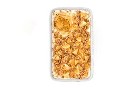 Homemade toffee apple ice cream with cinnamon crumbles, toffee sauce and apple chunks in a metal container isolated on white background. Top view.の写真素材