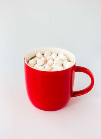 Red mug filled with hot chocolate and mini marshmallows isolated on white. Angled view.の写真素材