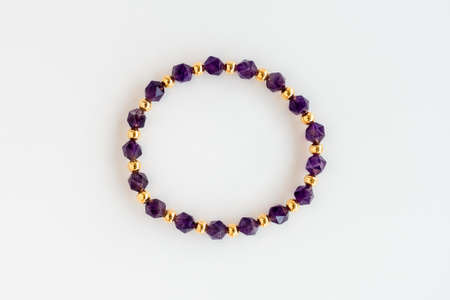 Amethyst bracelet with rare, unique polygonal beads and round gold beads isolated on white background. Top view. Handcrafted jewelry. Property release signed by artist.の写真素材
