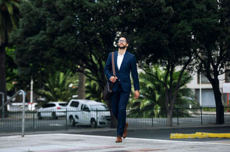 Portrait of a young man in a blue suit and glasses walking on the streetの写真素材