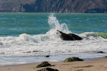 water splashing into rock on beachの写真素材