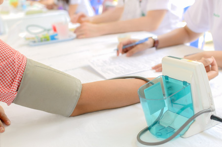 a nurse measuring patient's blood pressure by using a digital blood pressure meter