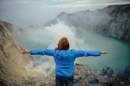 Sulfur mines,kawah ijen,indonesia.Sulfur mines view point.High angle shots.People look at sulfur mines.Women standing volcano views.Women are raising handsの写真素材