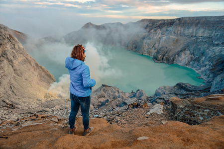 Sulfur mines,kawah ijen,indonesia.Sulfur mines view point.High angle shots.People look at sulfur mines.Women standing volcano views.Women are raising handsの写真素材