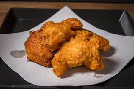 Fried chicken wings on a black plate, on a wooden table.の写真素材