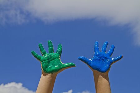 Brightly painted hands against blue skyの写真素材