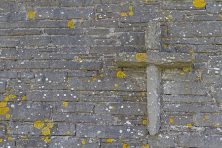 Stone cross on stone wall with mossの写真素材