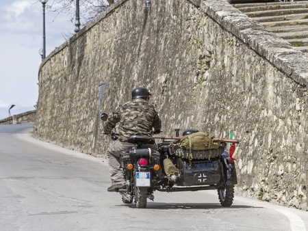 Motorcyclists, dressed in camouflage and equipped with rifle travels through the streets of an Italian cityの写真素材
