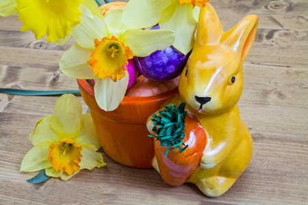 Easter still life with little porcelain bunny and spring flowers on wood background