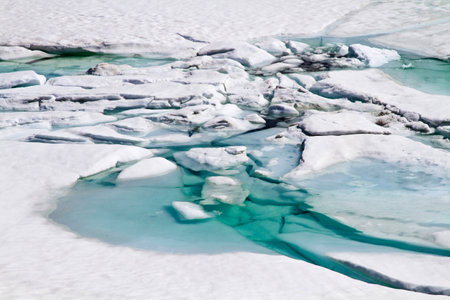 Mountain winter mood on ice lake on a sunny May day on the Sognefjellsvegen in Jotunheimenの写真素材
