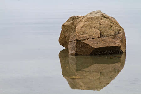 Rock lying with reflection in waterの写真素材