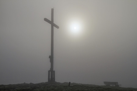 Summit cross of Heigl head in the Bavarian Alps with diffuse sun and fogの写真素材