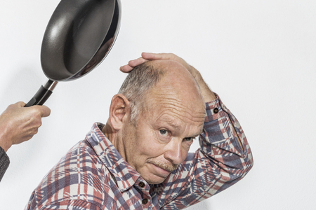Man tries to protect itself from blows with a frying panの写真素材