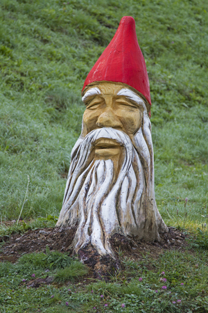 Fancifully worked and painted tree trunks in dwarven shape stand at the edge of the roadの写真素材