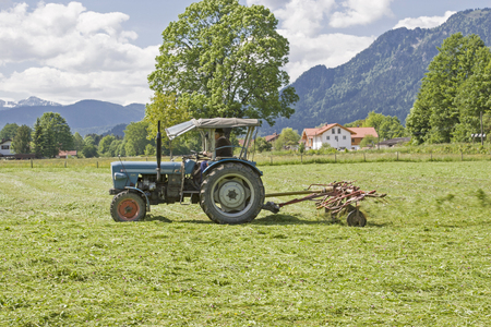 Farmer with old tractor and hay tedder in a meadow at the hay harvestのeditorial素材