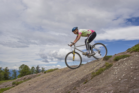 Over steep and rocky passages the mountain biker drives concentrated into the valleyの写真素材
