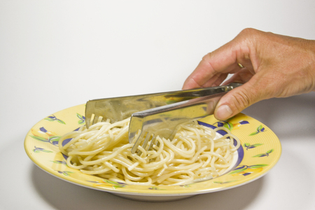 Spaghetti is distributed to the plates with a special kitchen utensil called spaghetti tongsの写真素材