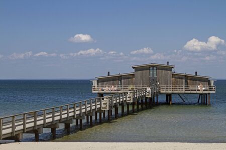 On the beautiful sandy beach of the swanky Swedish seaside resort of Bastad a jetty with a characteristic bath house. which is built on wooden stiltsの写真素材