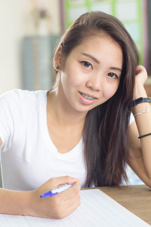 A woman wearing white t-shirt writing.の写真素材