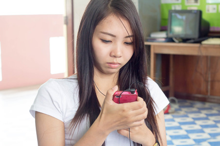 A woman wearing white t-shirt using mobileの写真素材