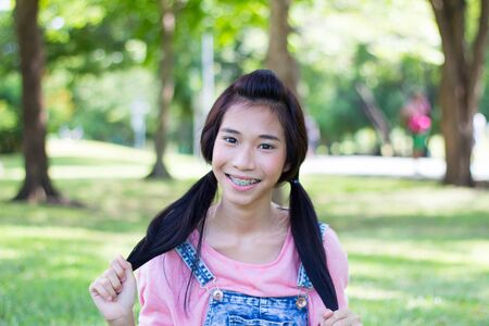 Portrait of thai student teen beautiful girl pink shirt Denim Shorts happy and relax On Parkの写真素材
