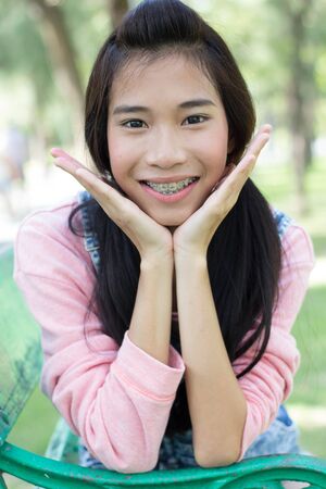 Portrait of thai student teen beautiful girl pink shirt Denim Shorts happy and relax On Park
