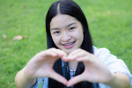 Portrait of thai student teen beautiful girl Dress white smile give heart and relax On Park