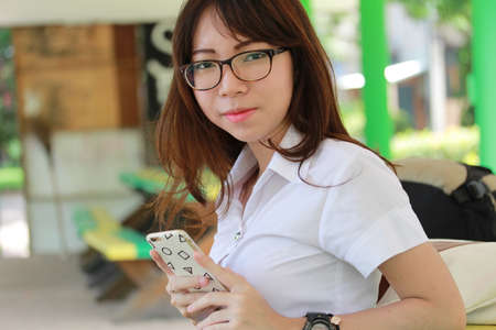 Portrait of thai woman student university beautiful girl using her smart phone.