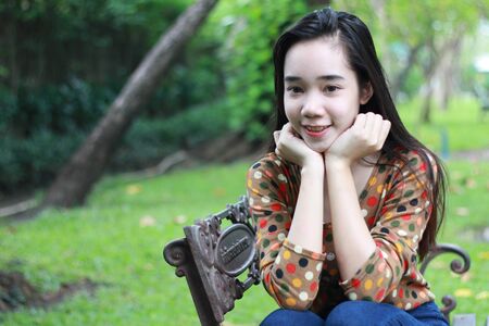 Portrait of thai student teen beautiful girl relax and smile in park.の写真素材