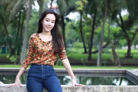 Portrait of thai student teen beautiful girl relax and smile in park.の写真素材