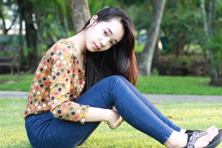 Portrait of thai student teen beautiful girl relax and smile in park.の写真素材