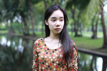 Portrait of thai student teen beautiful girl relax and smile in park.