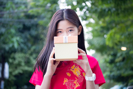 Portrait of thai teen beautiful girl in Chinese dress, happy new year and give gift, relax and...