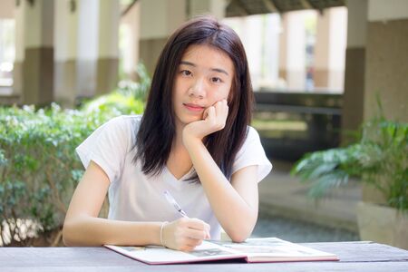 asia beautiful girl writing on a book and looking at cameraの写真素材
