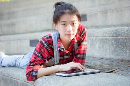 asia thai teenager Women Scotch T-Shirt using her tablet.の写真素材