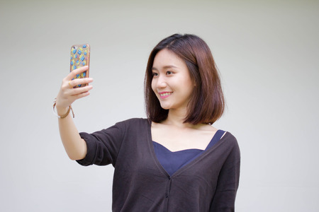 Portrait of thai adult student university beautiful girl using her smart phone Selfieの写真素材