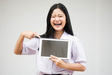 Portrait of thai high school student uniform beautiful girl using her tablet.の写真素材