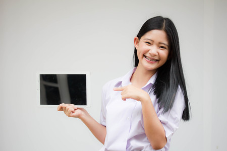 Portrait of thai high school student uniform beautiful girl using her tablet.の写真素材