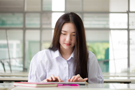 Portrait of thai high school student uniform beautiful girl using her tablet.の写真素材