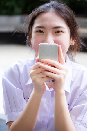 Portrait of thai china teen beautiful girl using her phone and smileの写真素材