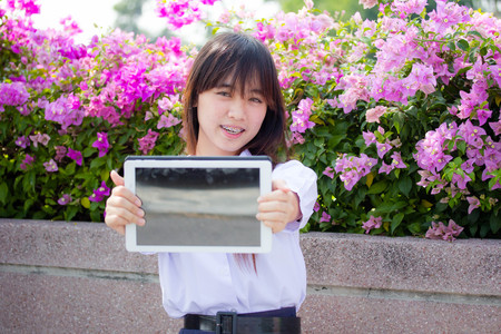 Portrait of thai high school student uniform beautiful girl using her tablet.の写真素材