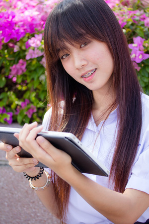 Portrait of thai high school student uniform beautiful girl using her tablet.の写真素材