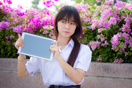 Portrait of thai high school student uniform beautiful girl using her tablet.の写真素材
