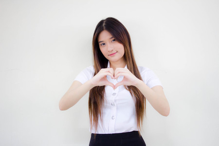 Portrait of thai adult student university uniform beautiful girl give heartの写真素材