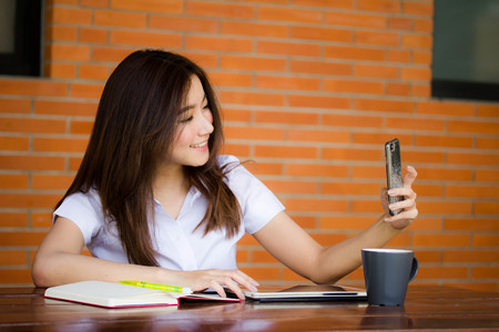 Portrait of thai adult student university uniform beautiful girl using her smart phone Selfieの写真素材