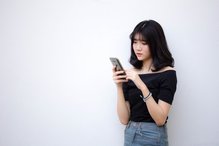 Portrait of thai vietnam teen beautiful girl using her phone and smileの写真素材