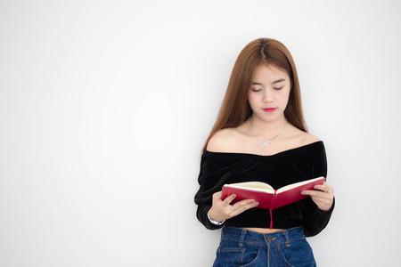 Portrait of thai adult beautiful girl reading red bookの写真素材